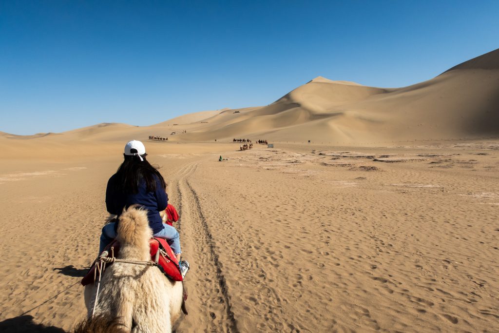 Hong riding a camel in the desert at Dunhuang, China
