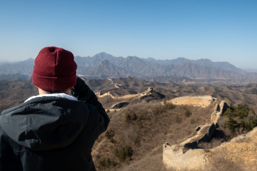 Eine Person genießt den Ausblick vom 24-Eyes Watchtower auf die wilde Panlongshan Chinesische Mauer.