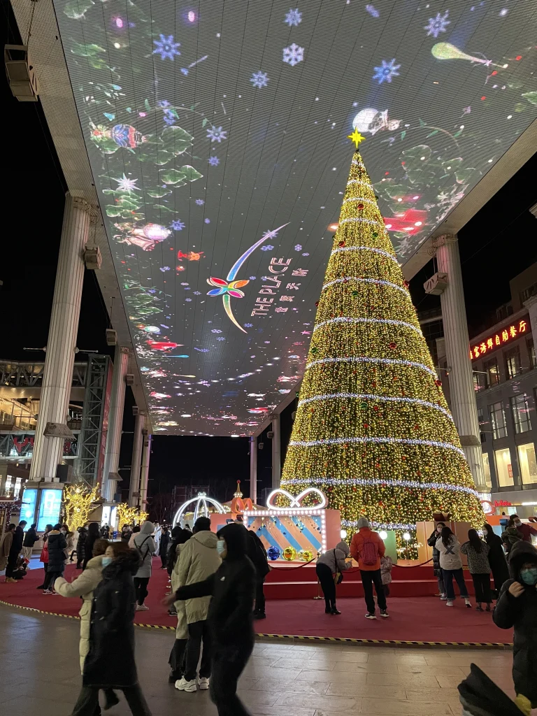 Large LED screen covering The Place shopping mall in Beijing with a giant Christmas tree.
