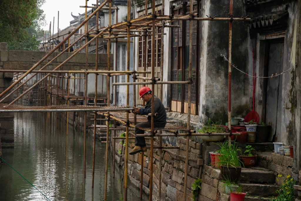 Ein Bauarbeiter macht Pause auf einem Baugerüst an einem Kanal in der Wasserstadt Luzhi.