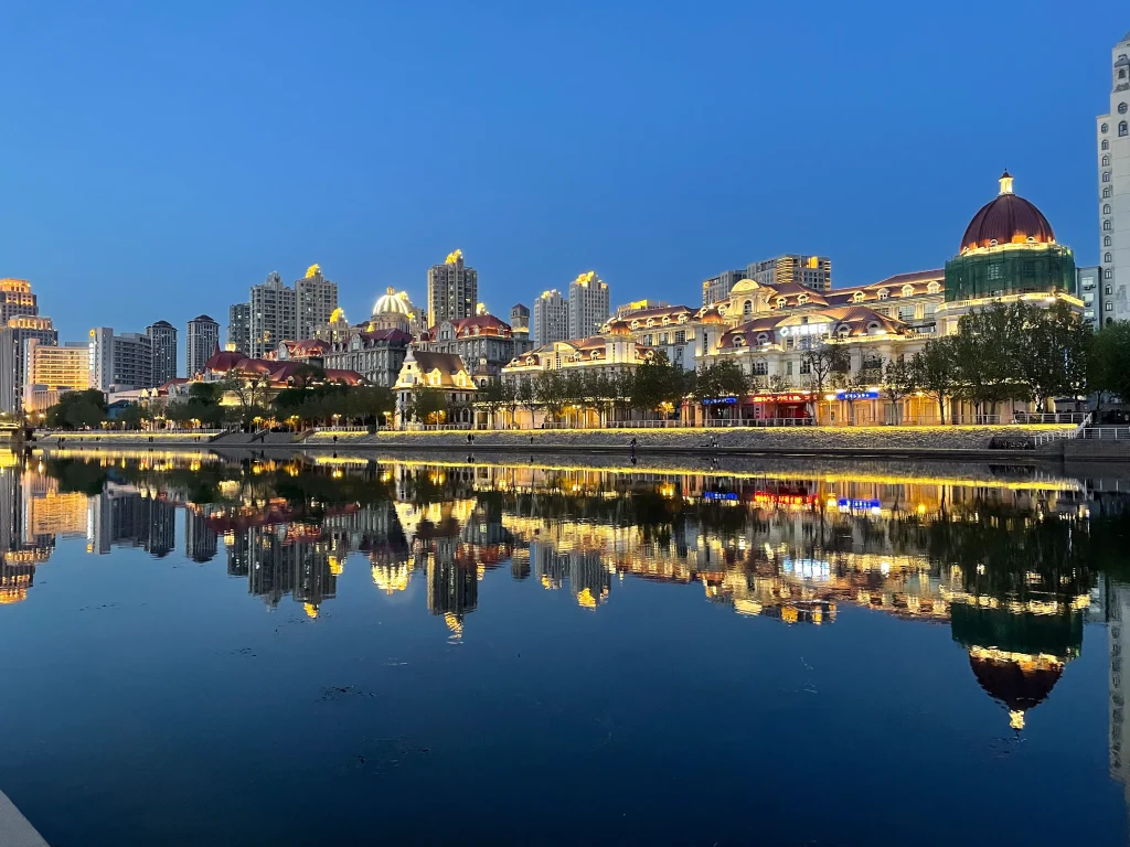 Beleuchtete Gebäude mit Wasserspiegelung am Haihe Fluss in Tianjin. 